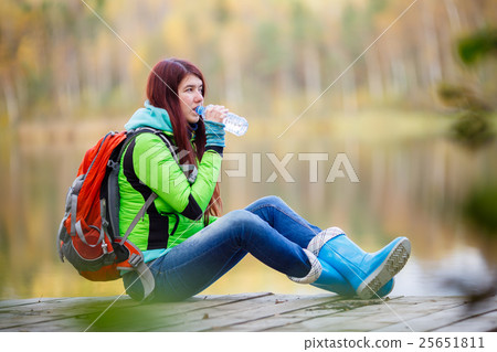 Young brunette drinking water from bottle at pond Young brunette drinking water from bottle at pond 25651811