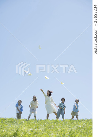 Elementary school students and teachers who fly paper airplanes in the meadow 25655234