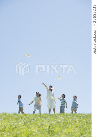 Elementary school students and teachers who fly paper airplanes in the meadow 25655235