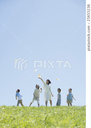 Elementary school students and teachers who fly paper airplanes in the meadow Elementary school students and teachers who fly paper airplanes in the meadow 25655236