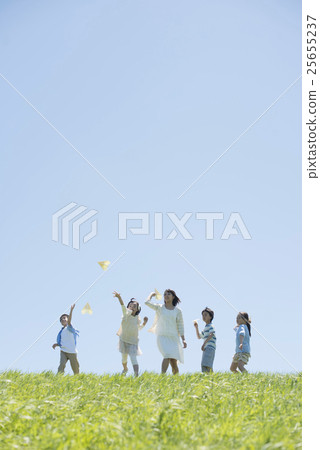 Elementary school students and teachers who fly paper airplanes in the meadow 25655237