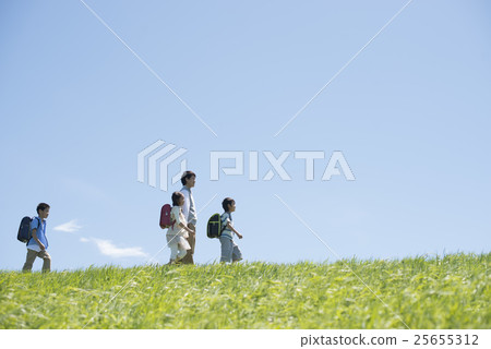 Elementary school students walking along the grass and teachers 25655312