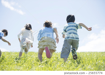 Rear appearance of elementary school student running on grassland 25655774