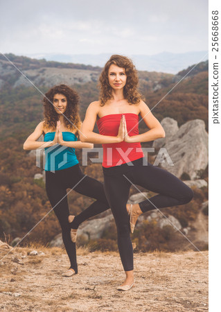 Two girls are doing yoga in mountains landscape Two girls are doing yoga in mountains landscape 25668668