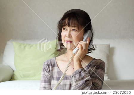 A senior woman talking on a fixed phone 25672030