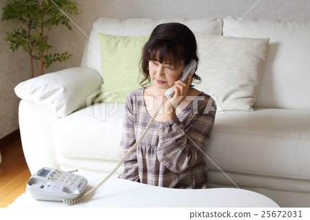 A senior woman talking on a fixed phone 25672031