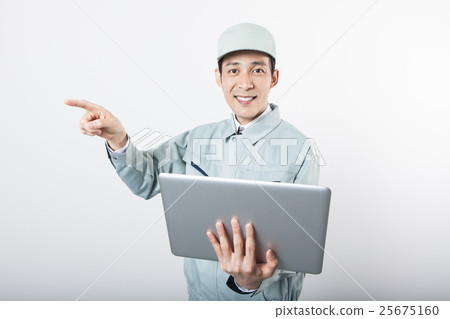 一個男人帶著工作服,拿著一台個人電腦,觸摸他的手指 一個男人帶著工作服,拿著一台個人電腦,觸摸他的手指 25675160