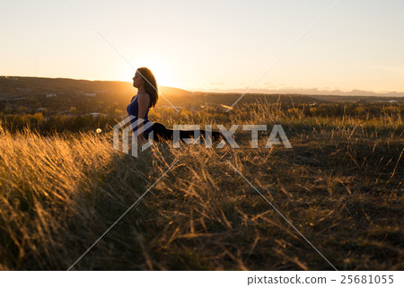 Woman doing yoga upward dog pose during sunset 25681055
