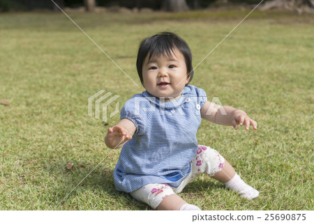 A baby with a smile playing on the lawn 25690875