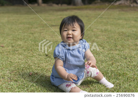 A baby with a smile playing on the lawn A baby with a smile playing on the lawn 25690876