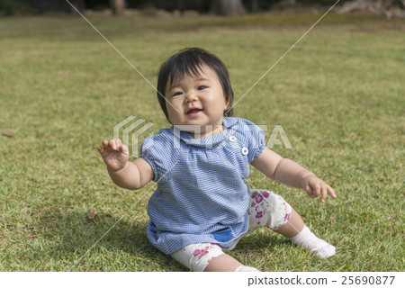 A baby with a smile playing on the lawn A baby with a smile playing on the lawn 25690877