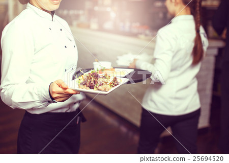 Waiters carrying plates with 25694520