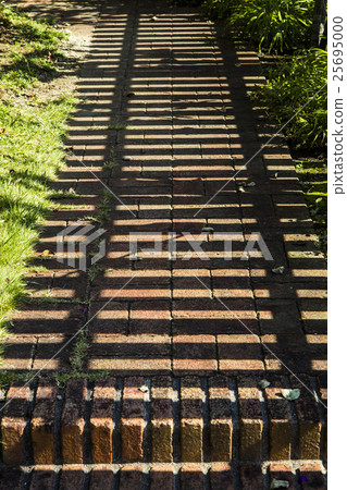 The shadow of the fence falls on the brick path The shadow of the fence falls on the brick path 25695000