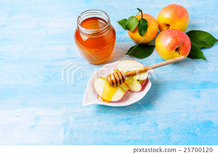 Apple slices with honey on blue wooden background Apple slices with honey on blue wooden background 25700120