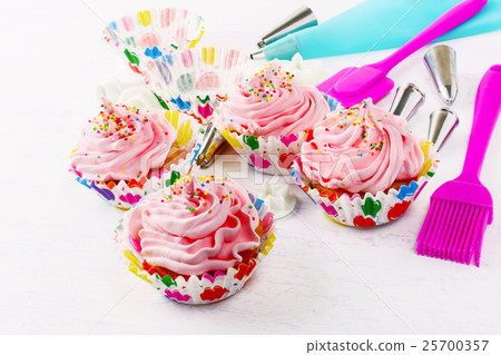 Cupcake with cream swirl and confectionery syringe 25700357