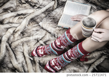 female legs in Christmas socks with a book and 25711471