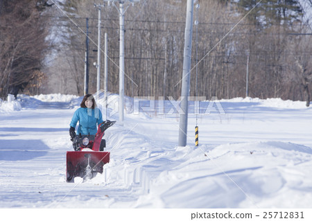 A woman snow removing A woman snow removing 25712831