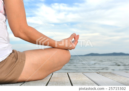 Woman practicing yoga meditation on the beach Woman practicing yoga meditation on the beach 25715302