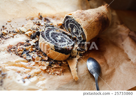 roll with poppy seeds on baking paper roll with poppy seeds on baking paper 25733860