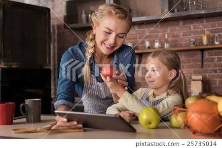 Smiling girl showing an apple to her mother 25735014