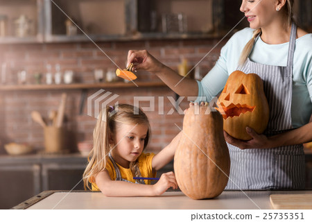 Amused mother making jack o lantern with her 25735351