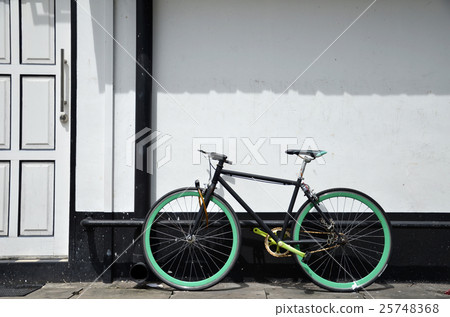 Bicycle leaning and white painted brick wall Bicycle leaning and white painted brick wall 25748368