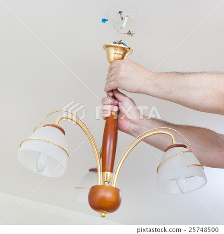electrician removes hanging ceiling light 25748500