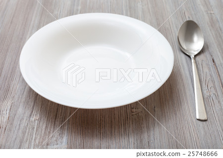 white deep plate and spoon on gray brown board 25748666