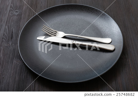 black plate with parallel knife, spoon on dark 25748682