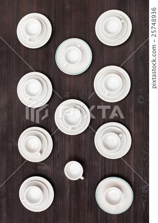 top view of cups and saucers on dark brown table 25748936
