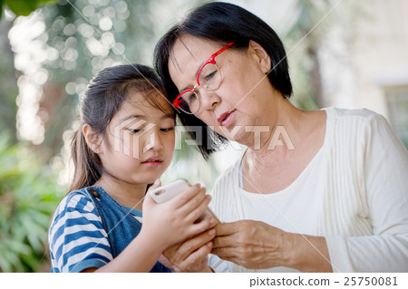 Little Asian girl using mobile phone with grandmom 25750081