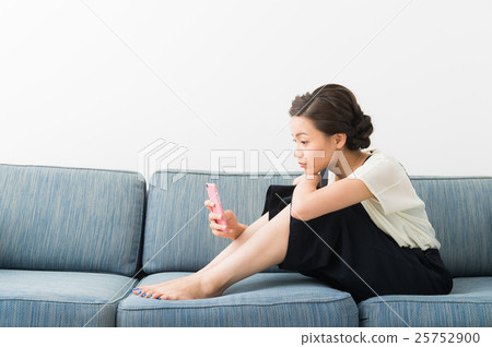 A woman sitting on a sofa (in her twenties) 25752900