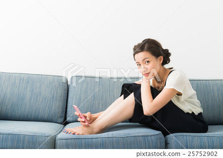 A woman sitting on a sofa (in her twenties) 25752902
