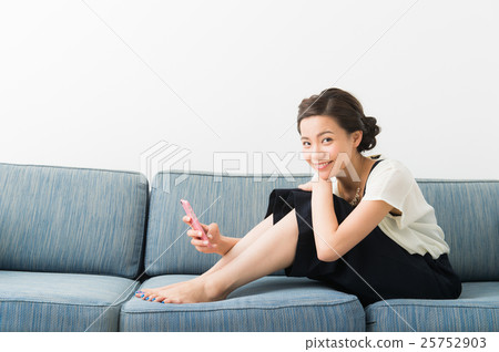 A woman sitting on a sofa (in her twenties) A woman sitting on a sofa (in her twenties) 25752903
