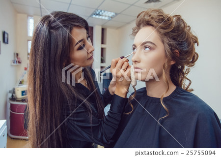 Make up artist doing professional makeup of young 25755094