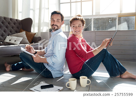 Middle-aged couple sitting on floor near window 25755599