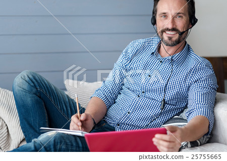 Stock Photo: Smiling bearded man with headphones and laptop