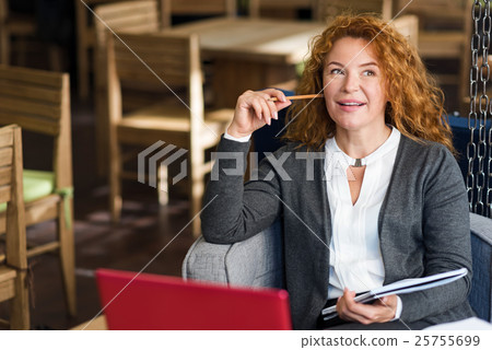 Smiling thoughtful woman in cafe 25755699