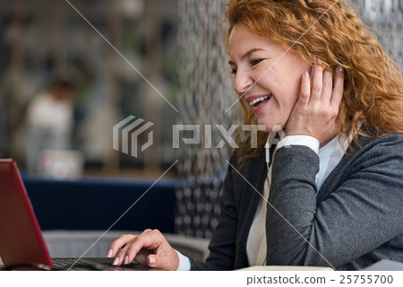 Side view of smiling woman using laptop 25755700