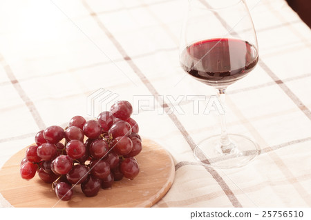 Red Wine in Glass with Grapes on The Table 25756510