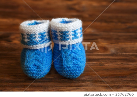 Blue hand made crochet baby booties on wooden Blue hand made crochet baby booties on wooden 25762760