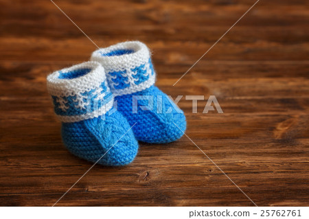 Blue hand made crochet baby booties on wooden Blue hand made crochet baby booties on wooden 25762761