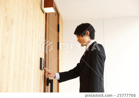 A young man in a suit pushing an interphone 25777708