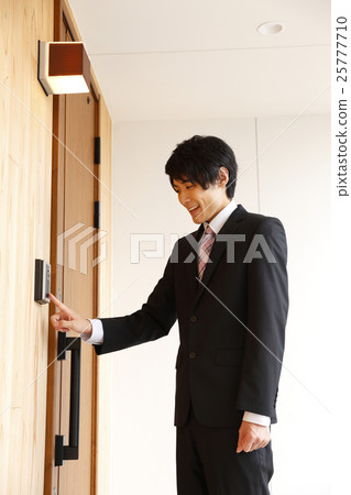 A young man in a suit pushing an interphone 25777710