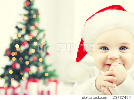 happy baby in santa hat over christmas tree lights 25787494