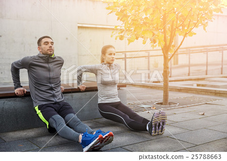 couple doing triceps dip on city street bench 25788663