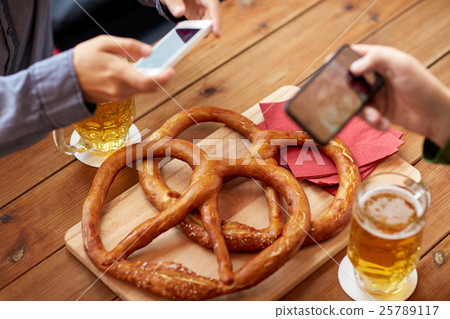 close up of hands picturing pretzel by smartphone close up of hands picturing pretzel by smartphone 25789117
