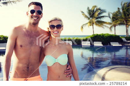 happy couple in swimwear hugging over hotel resort happy couple in swimwear hugging over hotel resort 25789214
