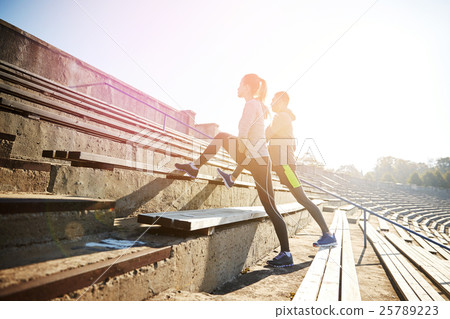 couple stretching leg on stands of stadium couple stretching leg on stands of stadium 25789223