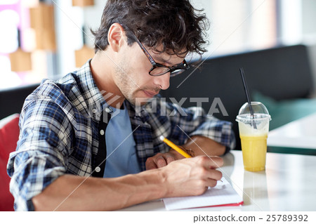 man with notebook and juice writing at cafe 25789392